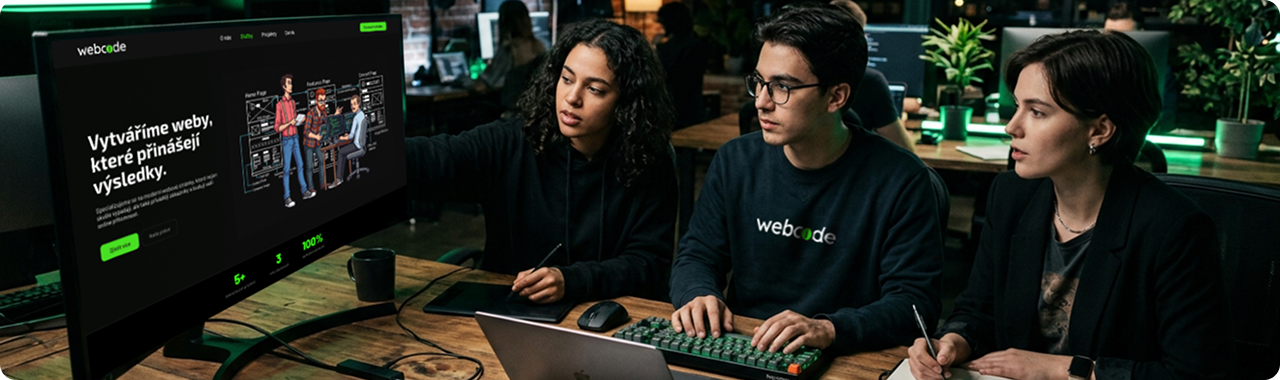 Tým spolupracuje nad návrhem webu na velkém monitoru.
